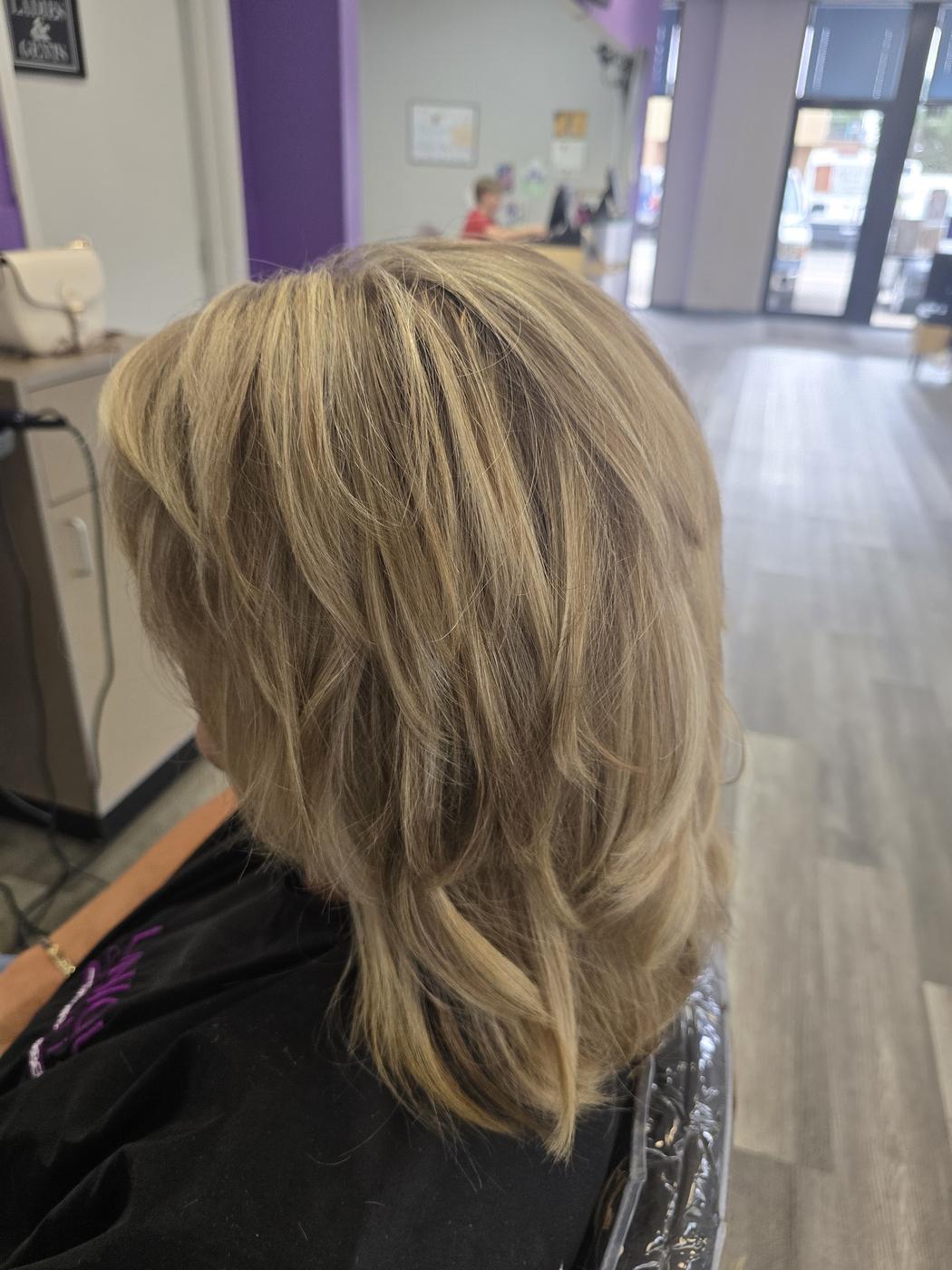 A finished layered haircut, with the salon's own purple-walled interior and storefront visible behind